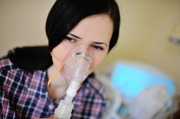 Adult pretty girl with inhaler in the clinic