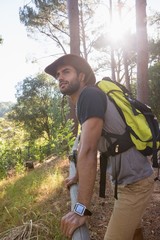 Man with backpack leaning on wooden fence in the forest