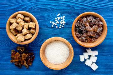 lumps of sugar in bowls on blue table background top view