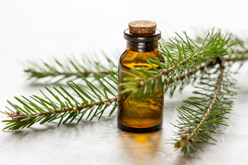 cosmetic spruce oil in bottles with fur branches on white table background