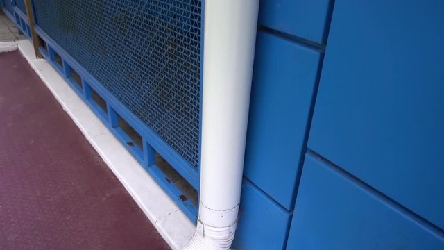 white downpipe on the background of blue wall.