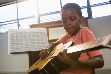 Naklejka premium Boy playing guitar in class