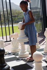 Girl playing large chess on sunny day
