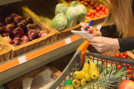 Young attractive woman checking her shopping list at the supermarket
