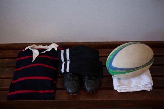 Rugby ball with clothes and shoes on wooden bench