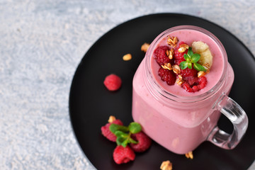 Raspberry smoothie with banana, yogurt and oatmeal on a gray, concrete background.