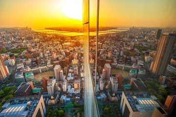 Aerial view of Osaka City central business downtown and Yodo River with its bridges at sunset. Osaka Skyline from Floating Garden Observatory Umeda Sky Building, Japan, reflect in the glass.