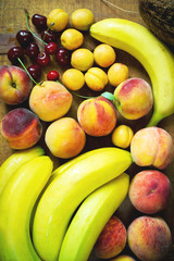 Fresh fruit variation. Ripe bananas, peaches, apricots and cherry on the table, top view