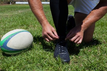 Rugby player tying shoes on field