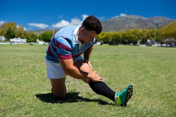 Young rugby player stretching on grassy field
