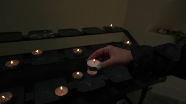 Young Woman Sets A Lit Candle Offering On Altar At The Oude Kerk (Old Church) In Amsterdam, Netherlands
