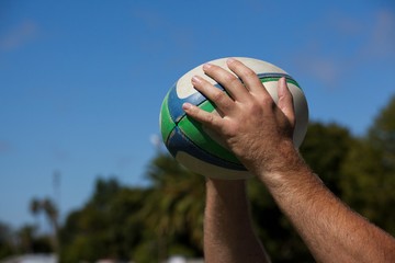 Player holding rugby ball against sky