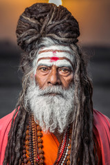 Portrait of sadhu standing with sunrise behind him, Varanasi, India.