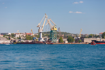 Marine loading port for large ships unloading zone with cranes on background of the city. Shipyard (panorama)