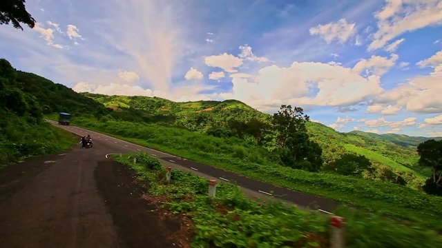 Motion along Curvy Country Road among Green Hilly Landscape