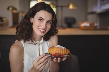 Portrait of beautiful woman holding croissant in plate