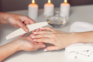 Obraz na płótnie Canvas Spa salon. Beautiful woman hands having nail filing with nail file by manicurist. Cosmetic procedure, manicure on female hand