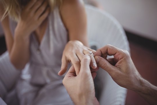 Man putting engagement ring on woman's hand