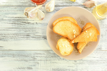 Plate with tasty garlic French bread slices on wooden table