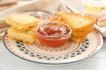 Plate with tasty garlic French bread slices on wooden table