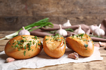 Tasty buns with garlic and herbs on paper