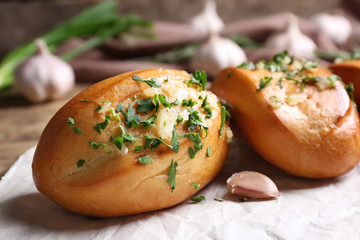 Tasty buns with garlic and herbs on paper, closeup