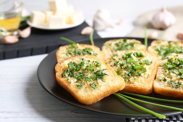 Tasty bread slices with garlic, cheese and herbs on plate