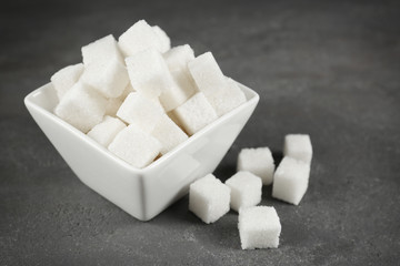 Bowl with sugar cubes on grey table