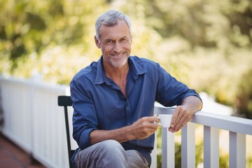 Portrait of mature man having a cup of coffee in balcony  - Powered by Adobe