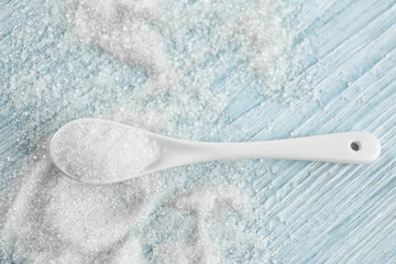 Spoon with sugar on wooden table