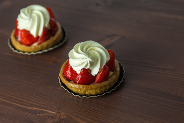 Two delicious strawberry tarts with chantilly cream - tartellete - on an ipe natural wood table