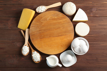 Dairy products with board on wooden table, top view
