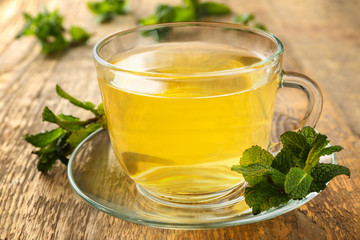 Cup of tea with mint leaves on wooden table