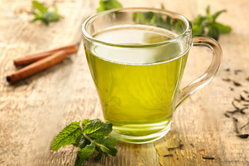 Cup of tea with mint leaves and cinnamon on wooden table