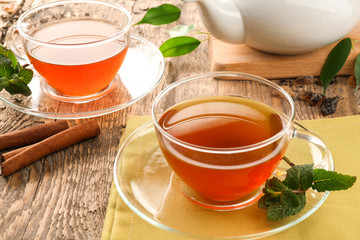 Cups of black tea with mint leaves on wooden table