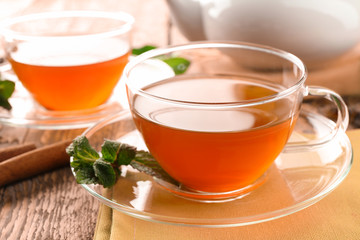 Cups of black tea with mint leaves on wooden table