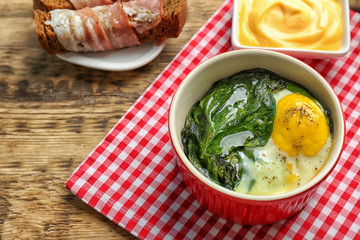 Delicious eggs Florentine in bowl and napkin on wooden table