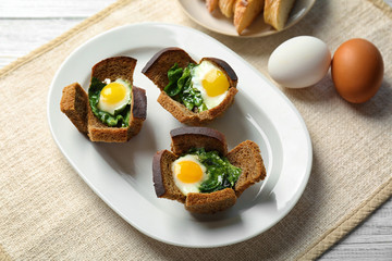 Plate with tasty eggs and spinach on wooden table