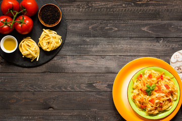 Tagliatelle with tomato and basil, made at home, on a wooden background.