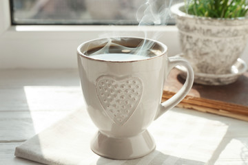 Cup of delicious coffee on window sill