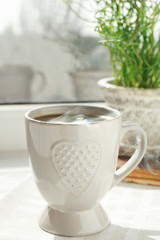 Cup of delicious coffee on window sill