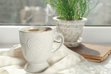 Cup of delicious coffee on window sill