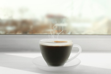 Matte glass cup of coffee on white window sill