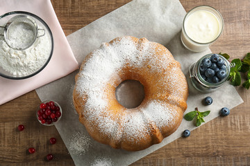Delicious freshly baked cake with powdered sugar on wooden kitchen table