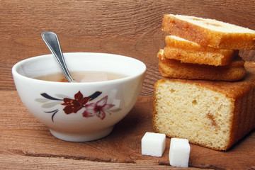 Black tea with sugar and cake with jam on wooden background