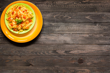Tagliatelle with tomato and basil, made at home, on a wooden background.