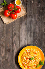 Tagliatelle with tomato and basil, made at home, on a wooden background.