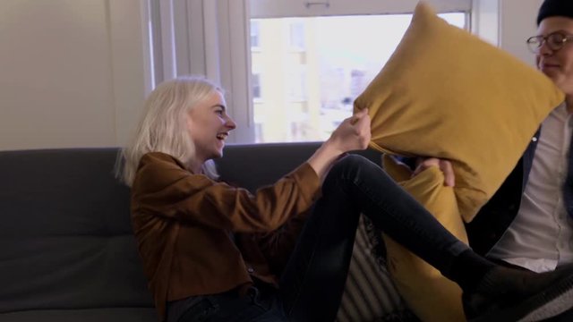 Playful Couple Bring A Load Of Stuff Into Their New Apartment, Then They Sit On Couch And Have A Cute Pillow Fight