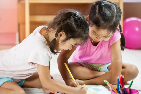 Two asian little girls  having fun to  paint with crayon together in vintage color tone