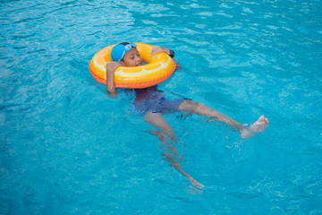Young boy swimming in pool with swim ring